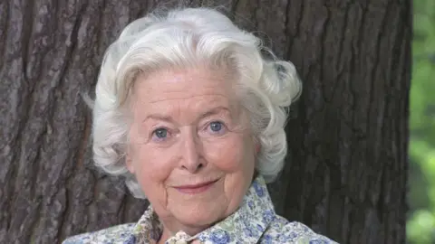 BBC June Spencer, pictured in 2003, standing by a tree in a flowery dress