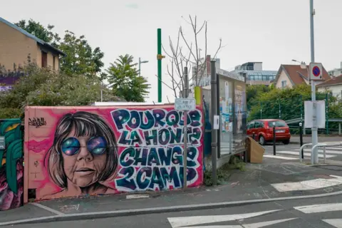 Getty Images A mural near a pedestrian crossing, with a picture of a woman with a short bob and round sunglasses with the words: 