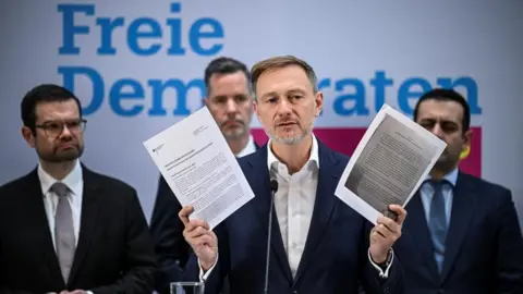 Reuters Christian Lindner holds up documents as he speaks to reporters after he was sacked by Olaf Scholz