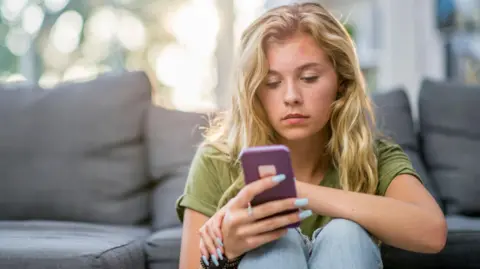 Getty Images A girl looks at her phone