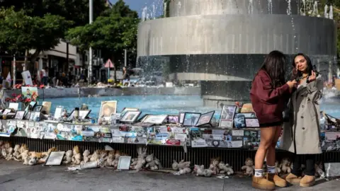 Reuters Israeli women in Tel Aviv stand near a makeshift memorial to hostages kidnapped by Hamas. Photo: 20 November 2024