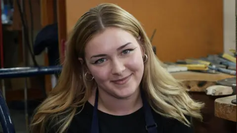 Hockley Mint Apprentice Abi sits and smiles at the camera