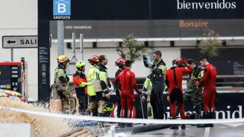 EPA-EFE/REX/Shuttershock Firefighters and rescue divers in uniform stand outside an underground car park.