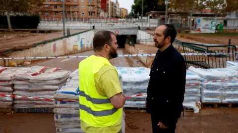 Reuters Guillermo Lujan, the mayor of Aldaia, stands in front of sandbags which have been placed to channel the water and prevent it from entering the town centre in anticipation of a new DANA in Aldaia, Valencia, Spain