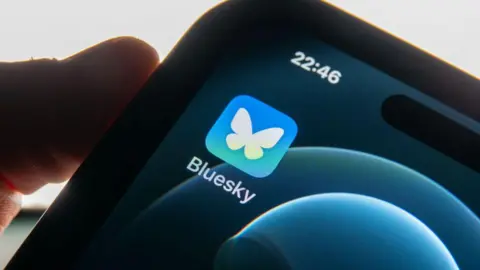 Getty Images A person holding a phone with the Bluesky logo on it