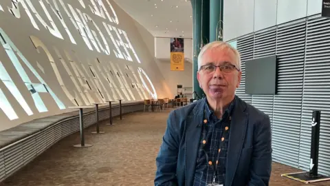 Dafydd Rhys sits in the Millennium Centre facing the camera 