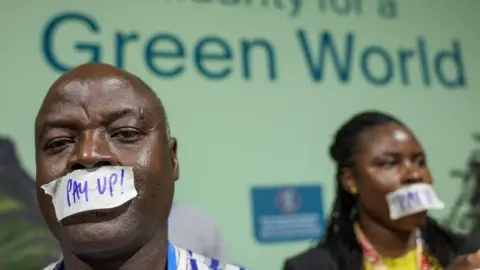 Reuters Two people wear tape over their mouths that reads 