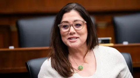 Getty Images Lori Chavez-DeRemer is seen seated in a congressional hearing room wearing glasses and a beige shirt. 