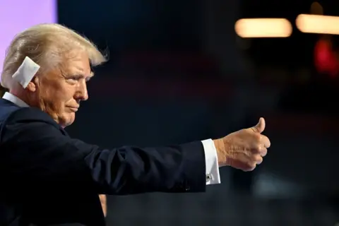 Bloomberg/Getty Images Donald Trump gives a thumbs up to the crowd at the Republican National Convention in Milwaukee. He has a white bandage on his right ear.