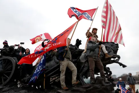 EPA Men atop a statue holding flags saying 