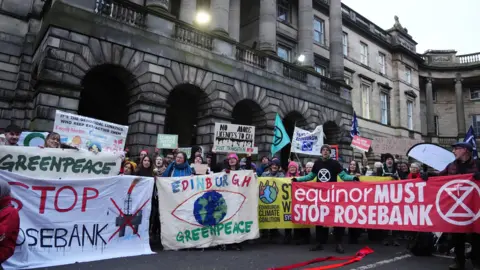 PA Media A group of protesters from climate organisations outside the Court of Session in Edinburgh. From left to right, one group are holding a greenpeace banner, which has the name of the organisation in green on a white banner. Below that is the words 