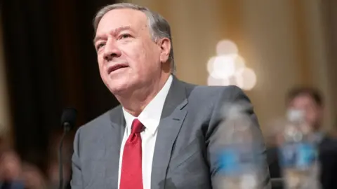 Reuters Mike Pompeo, who has neat grey hair brushed to the side, wears a grey suit, white shirt and red tie as he testifies before the House Select Committee in Washington