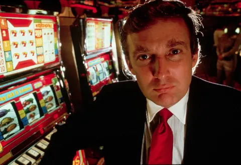 Getty Images Donald Trump poses in front of slot machines at the opening of the Taj Mahal casino in Atlantic City, New Jersey.