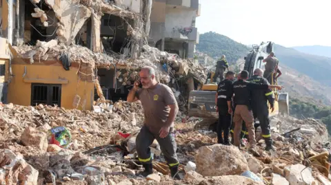 Reuters Lebanese Civil Defence first responders search through rubble after a deadly Israeli strike on an apartment building in Barja, central Lebanon (6 November 2024)