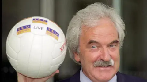 PA Media  Des Lynam in 1999 holding a football