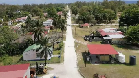 Yohan Henri Agalega's biggest village Vingt-Cinq - there is a narrow white road with small, detached red tin-roofed houses on either side