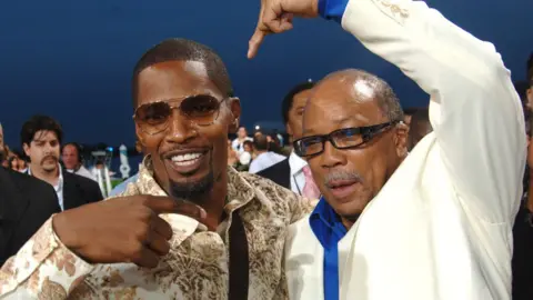 Getty Images Jamie Foxx and Quincy Jones playfully pointing each other with their arms around each other on the 2005 MTV Video Music Awards red carpet