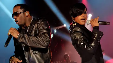 Getty Images Diddy and Dawn Richard singing into microphones together on stage with their backs to each other, at The Old Fruit Market in Glasgow in 2010