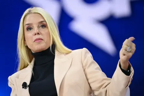 Getty Images Pam Bondi speaks during the annual Conservative Political Action Conference in Maryland in February. She has straight, blonde hair and wears a light beige blazer and black turtleneck.