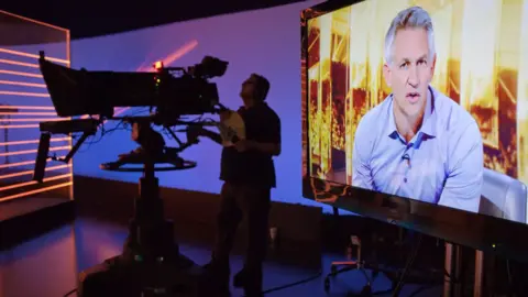 Getty Images Gary Lineker seen presenting Match of the Day in the show's studio, next to a cameraman operating a large studio TV camera