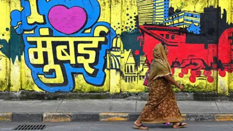 Getty Images A woman walks past a wall mural reading 'I love Mumbai' along a street in Mumbai on August 31, 2023. (Photo by Indranil MUKHERJEE / AFP) (Photo by INDRANIL MUKHERJEE/AFP via Getty Images)