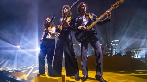 Getty Images Josh Dewhurst, Tom Ogden and Charlie Salt of Blossoms standing together on stage, all playing guitars, at Eventim Apollo in London on 2 November 2024