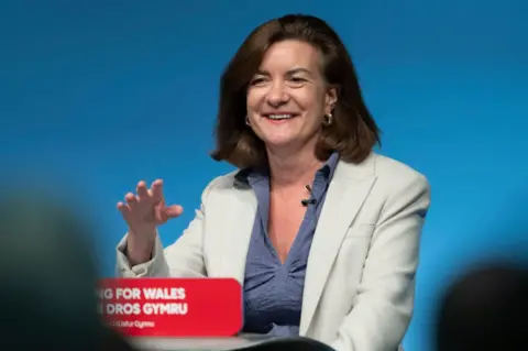 Getty Images Eluned Morgan smiling as she gives her speech to the Welsh Labour conference. She is standing behind a podium with red sign with the words 