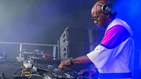 TRACEY WELCH/BBC DJ Spoony, wearing baggy t-shirt, glasses and headphones is controlling a music mixing desk