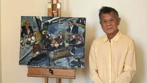 Pey Kan Su Pey Kan Su wearing a pale yellow shirt standing next to one of his paintings depicting a scene from the Post Office inquiry