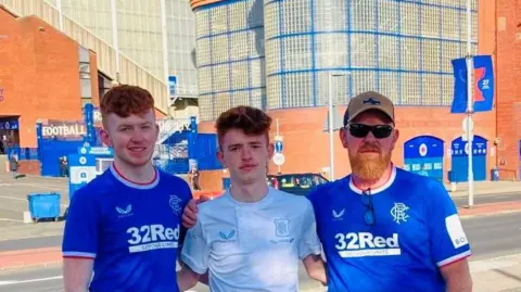 Richard Donaldson Three men looking at camera, two wearing blue Rangers FC tops, one with a ginger beard, cap and sunglasses, in front of Rangers' football stadium