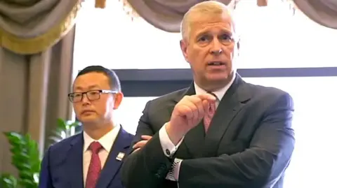 Supplied Yang Tengbo standing behind Prince Andrew