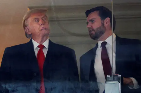 Reuters Donald Trump and JD Vance behind a glass panel, speaking to each other