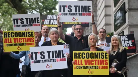 Getty Images Demonstrators outside the public inquiry in 2023 hold placards related to the infected blood scandal reading: 