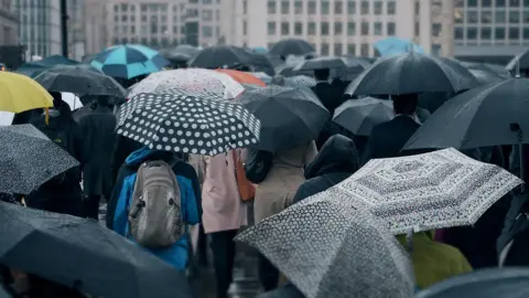 Getty Images People commuting with umbrellas