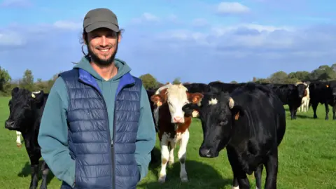 Lisa Louis Farmer Antoine Gomel stands in front of his cattle