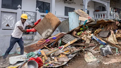 Getty Images A worker clears debris on a street in the city of Mamoudzou on the French Indian Ocean territory of Mayotte, after the cyclone Chido hit the archipelago