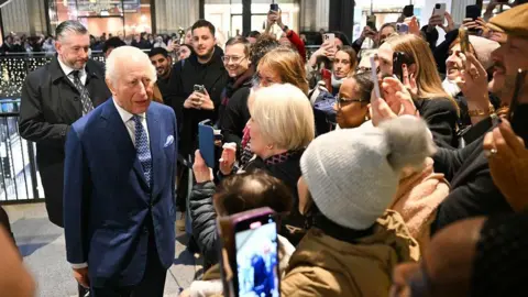 Getty Images The King is surrounded by members of the public, many of whom have their phones out recording him