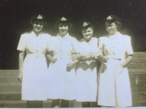 Anne Puckridge A black-and-white photo of Anne Puckridge and three other young women wearing military uniform.