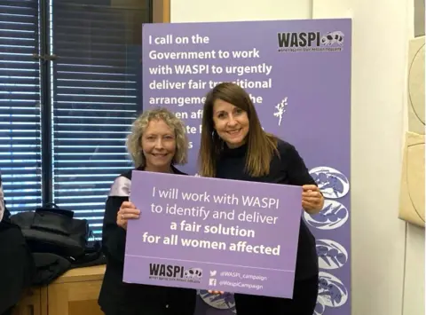 Waspi/PA Media Liz Kendall holds a purple placard reading: I will work with WASPI to identify and deliver a fair solution for all women affected. She is standing alongside a female campaigner in front of a sign promoting the Waspi women campaign.