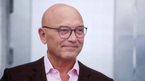 BBC/Shine TV Gregg Wallace in pink shirt and brown/maroon jacket 