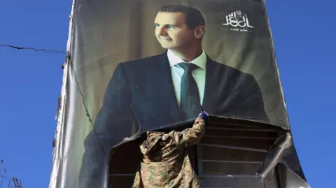 Getty Images An anti-government fighter tears down a portrait of Bashar al-Assad in Aleppo.