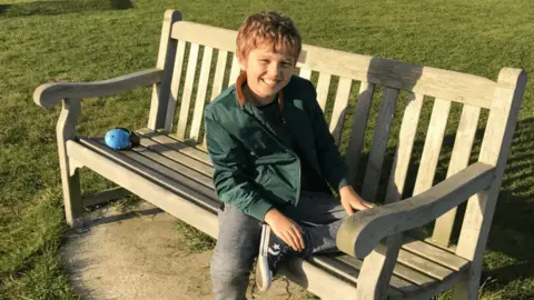 James Hunt Jude sits on a bench, smiling and looking directly at the camera