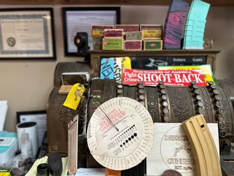 A vintage cash register is adorned with a sign that says 