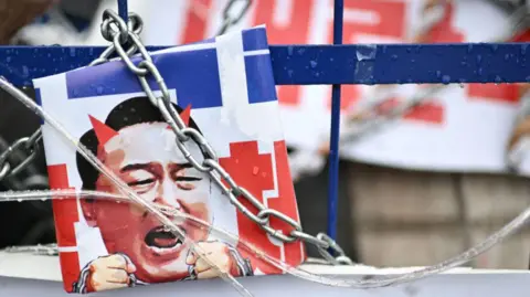 Getty Images A poster of Yoon with chains and devil's horns displayed at an anti-Yoon protest