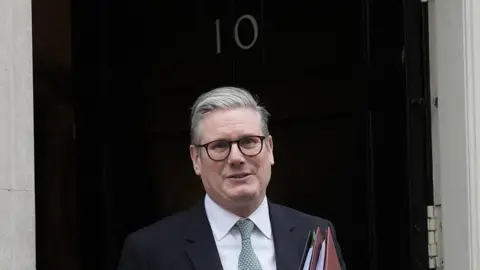 PA Media Sir Keir Starmer stands outside 10 Downing Street on his way to Prime Minister's Questions, holding a couple of red folders