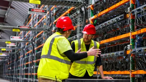 Getty Images Two workers in a datacentre in hi-vis jackets