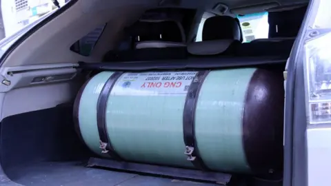 A large gas cylinder inside the boot of a car.