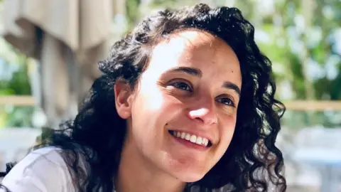 PA Media Handout image of Emily Damari smiling. She has curly black hair and is wearing a white top