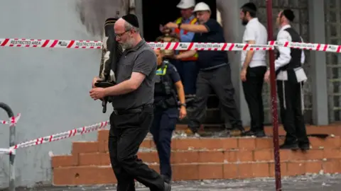 Getty Images A member of the Jewish community recovers an item from the Adass Israel Synagogue on December 06, 2024 in Melbourne, Australia. An arson attack on the Adass Israel Synagogue in Melbourne forced congregants to flee as flames engulfed the building early on Friday morning.