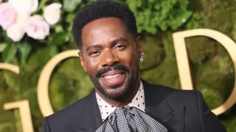 Getty Images US actor Colman Domingo arrives for the 82nd annual Golden Globe Awards at the Beverly Hilton hotel in LA on 5 January, 2025. He is wearing a black suit, a polka dot shirt and a huge black and white gingham cravat.